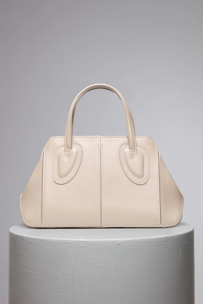 Cream leather handbag over the grey stand