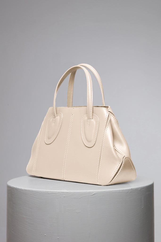 Cream leather handbag over the grey stand