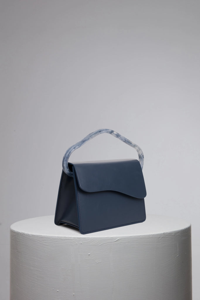 Navy geunine leather handbag on grey stand