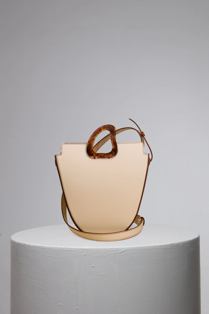 Cream leather handbag with bio-resin handle on grey stand