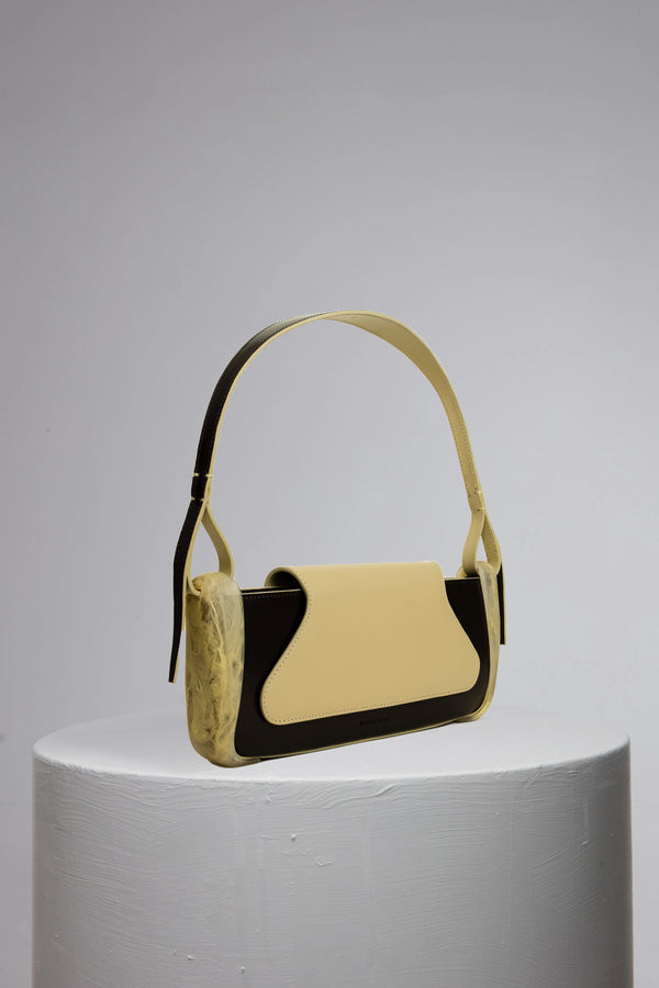 Yellowish geunine calf leather woman handbag with resin accessories on grey cylinder stand