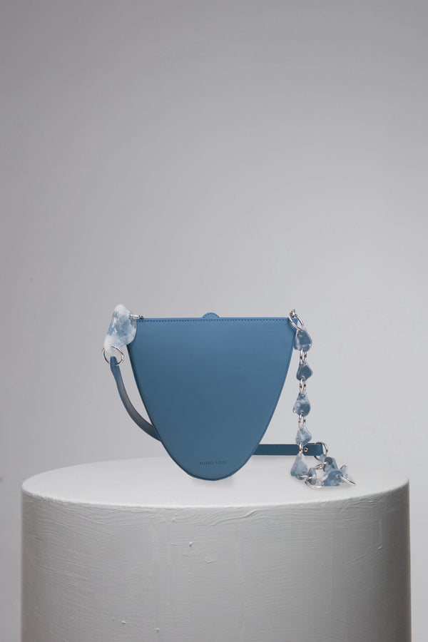 blue geunine calf leather woman handbag on grey cylinder stand