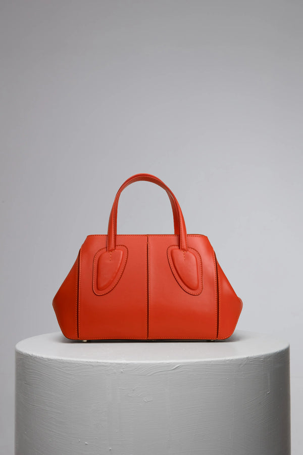 orange leather handbag on grey stand