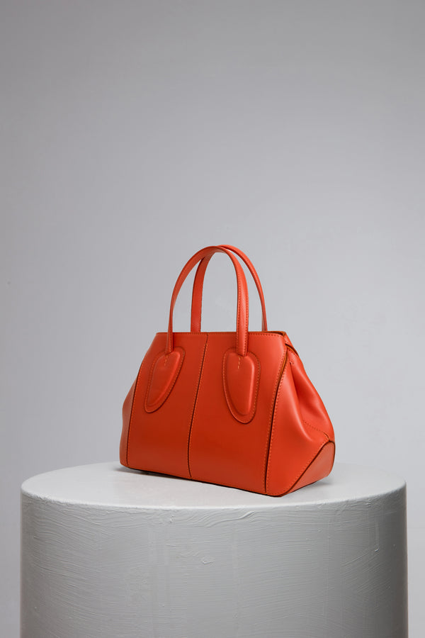orange leather handbag on grey stand