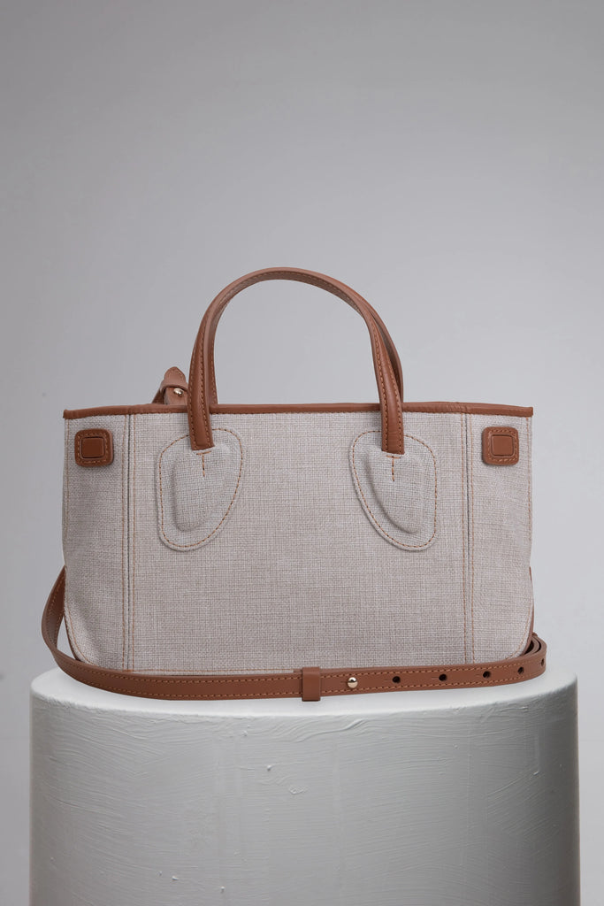 Canvas woman handbag with brand logo front on grey cylinder stand
