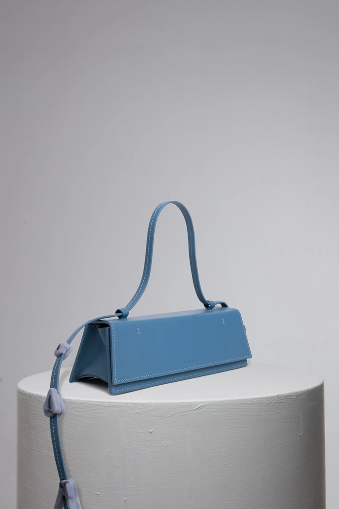 Blue geunine calf leather woman handbag  with resin accessories on grey cylinder stand