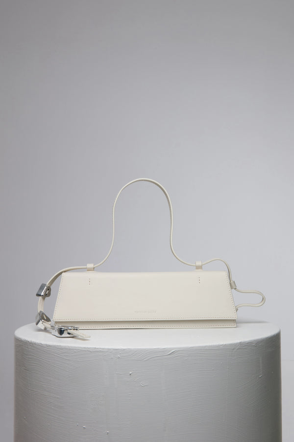 rectangular white handbag with strap on white stand