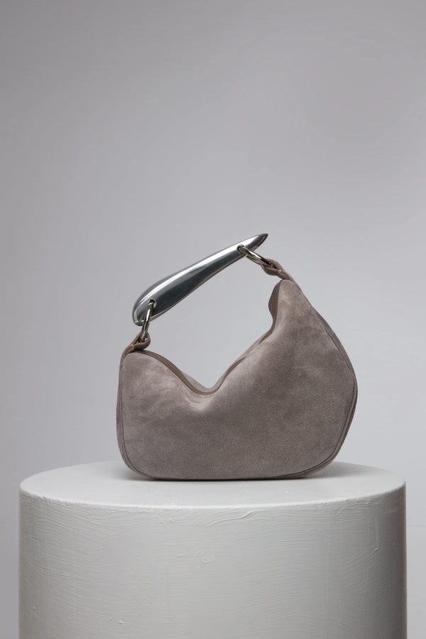 Grey suede leather soft handbag with metal handle on a white stand