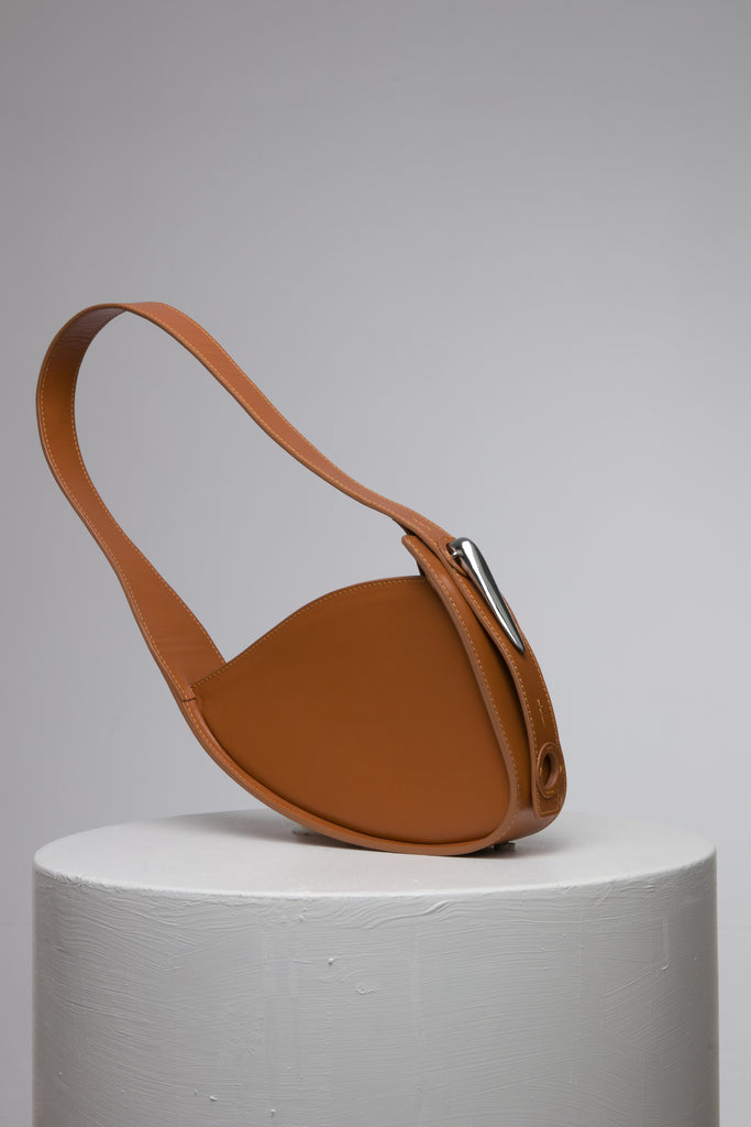 brown handbag with metal accessories on white stand