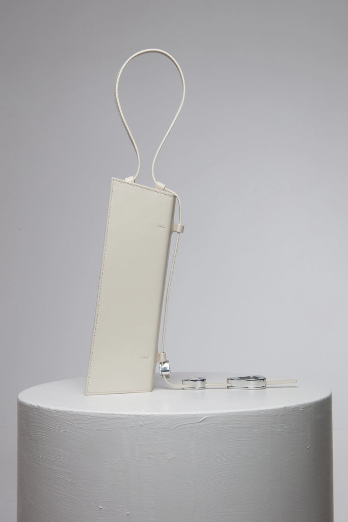 rectangular white handbag with strap on white stand