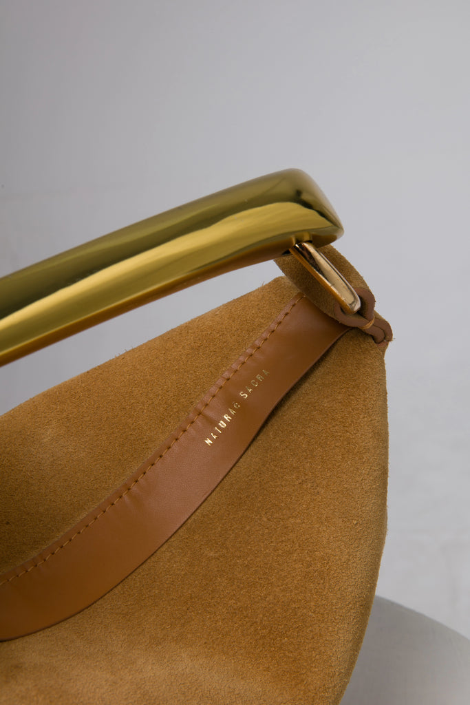 Brown suede leather soft handbag with metal handle on a white stand