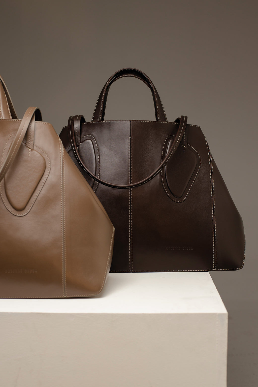 Calf leather maxi non-structured rectangle tote bag with non-removable two leather handle and two leather shoulder strap  on a white stand