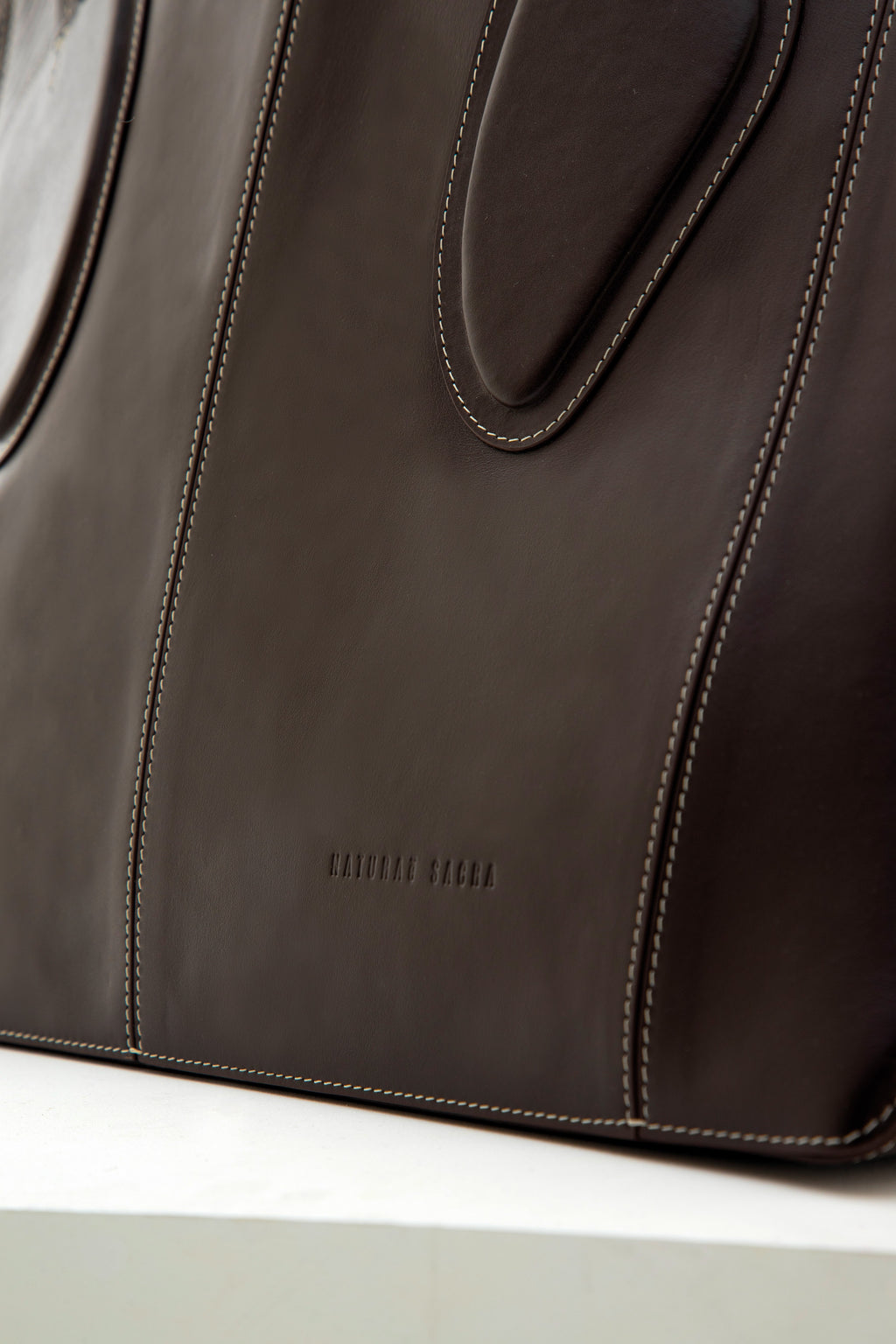 Calf leather maxi non-structured rectangle tote bag with non-removable two leather handle and two leather shoulder strap  on a white stand