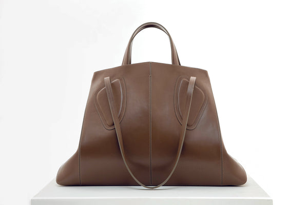 Calf leather maxi non-structured rectangle tote bag with non-removable two leather handle and two leather shoulder strap on a white stand