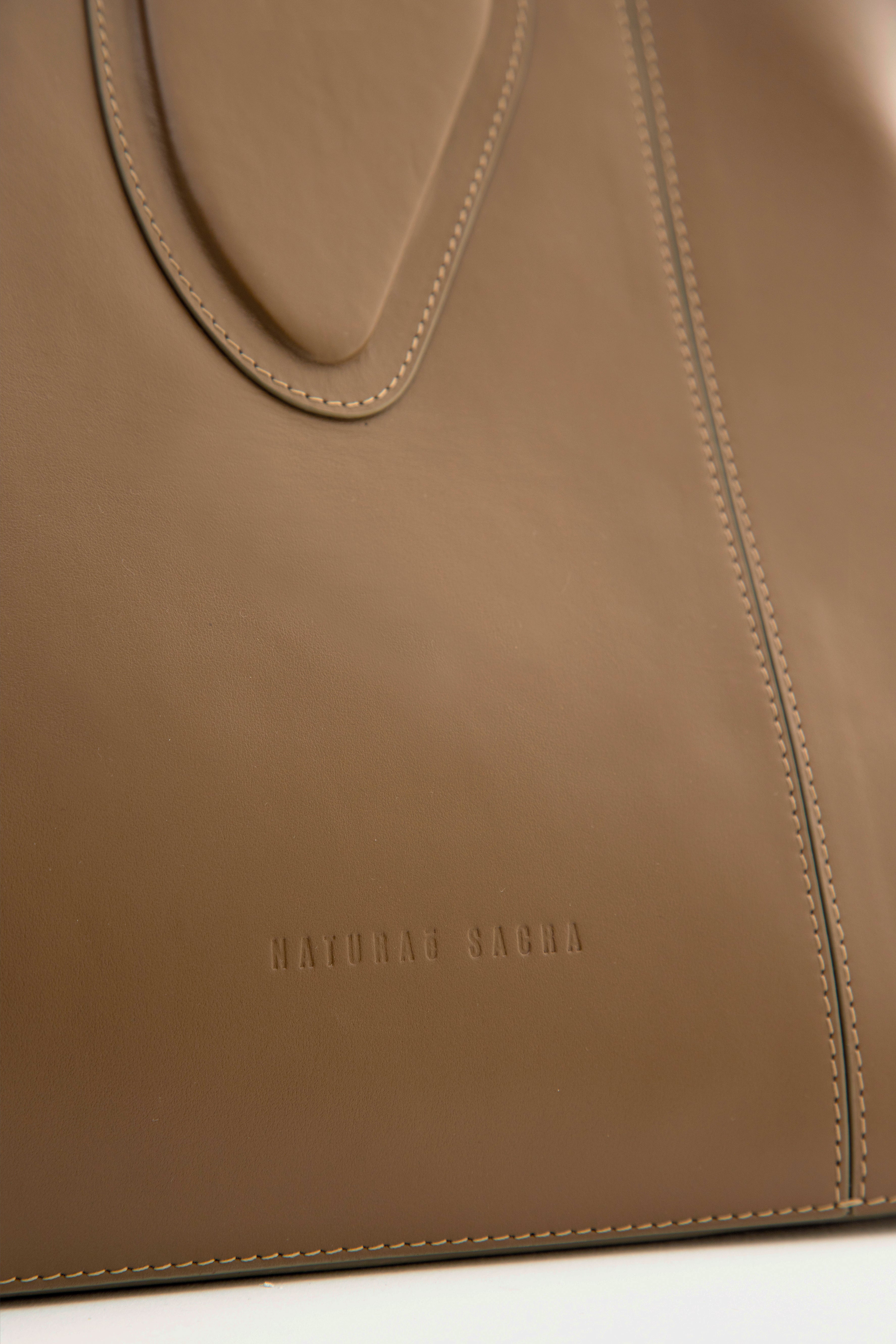 Calf leather maxi non-structured rectangle tote bag with non-removable two leather handle and two leather shoulder strap on a white stand