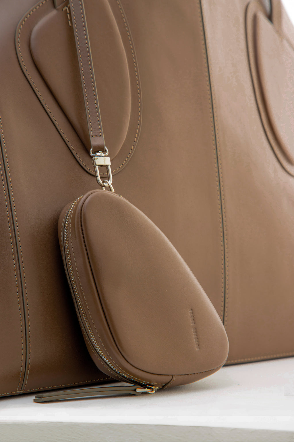 Calf leather maxi non-structured rectangle tote bag with non-removable two leather handle and two leather shoulder strap on a white stand