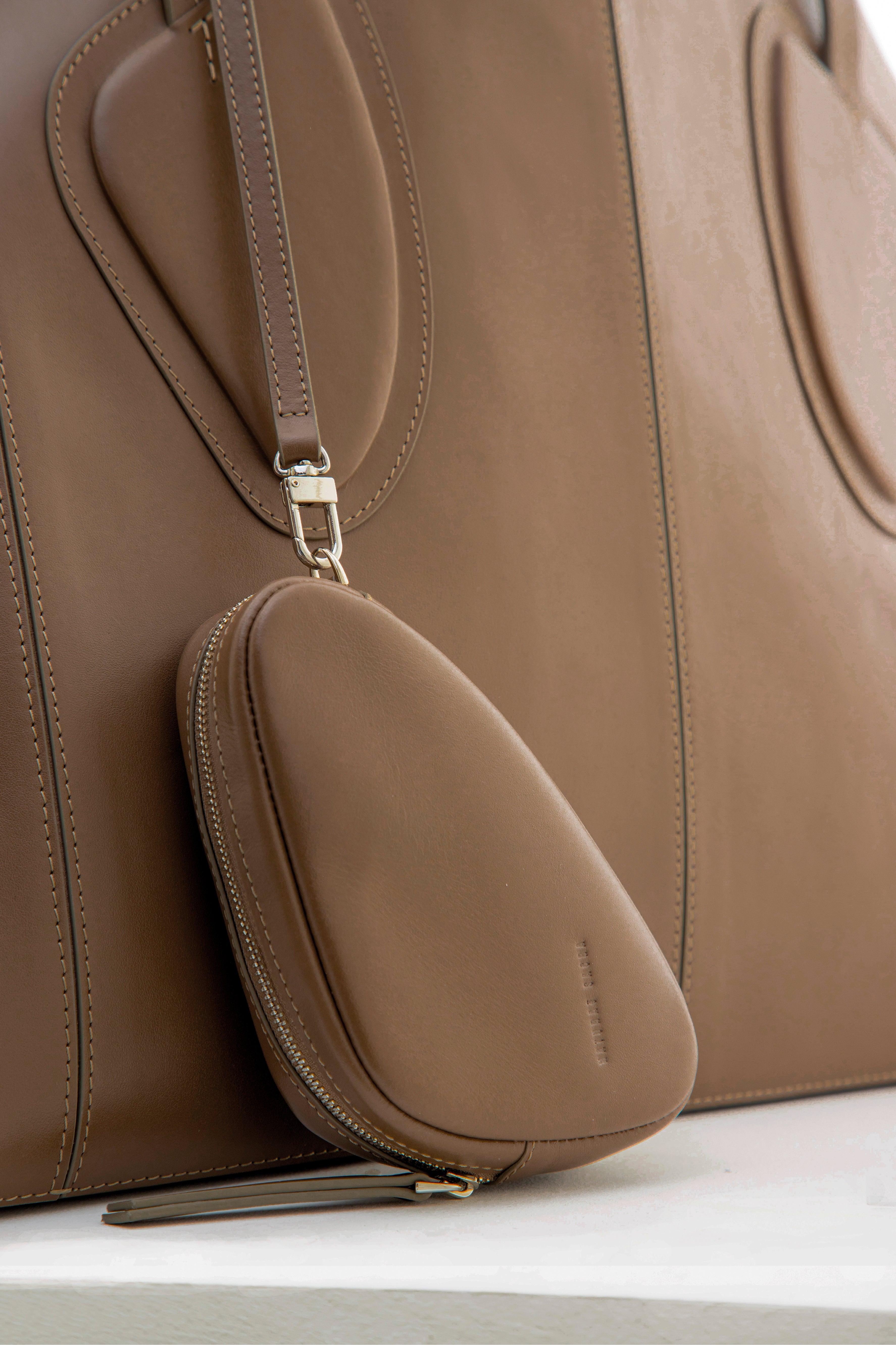 Calf leather maxi non-structured rectangle tote bag with non-removable two leather handle and two leather shoulder strap on a white stand