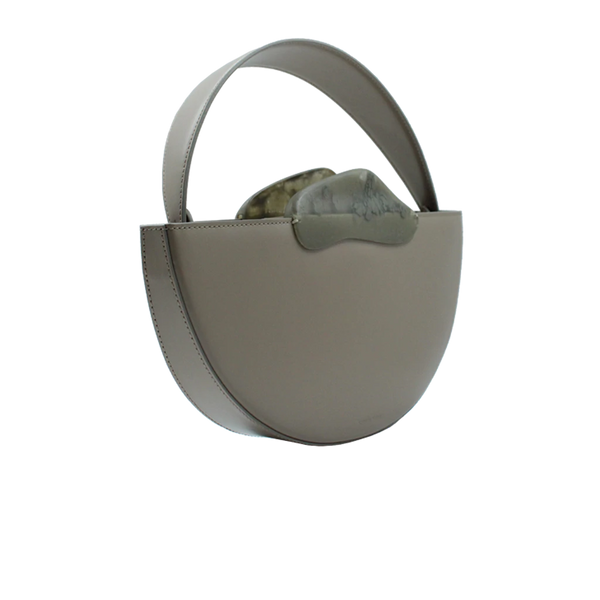 Flat topped oval structured taupe calf leather hand bag with two natural resin round handles and a removable calf leather strap on a white stand