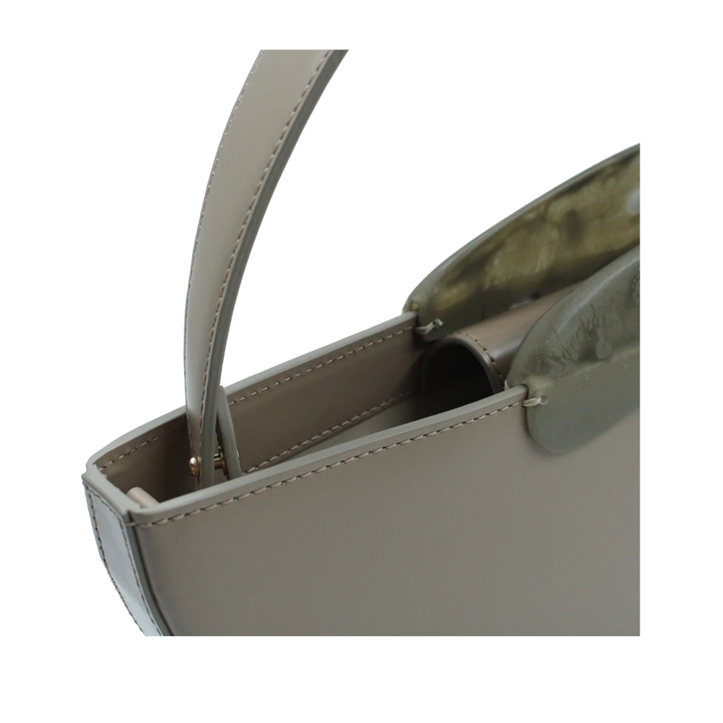 Flat topped oval structured taupe calf leather hand bag with two natural resin round handles and a removable calf leather strap on a white stand