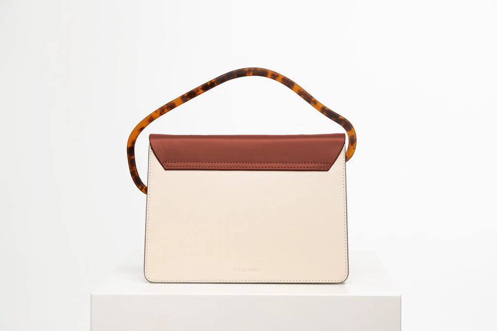 Rectangular women's handbag with a beige genuine leather body and a brown flap, bio resin handle and long shoulder handle, on a white stand.