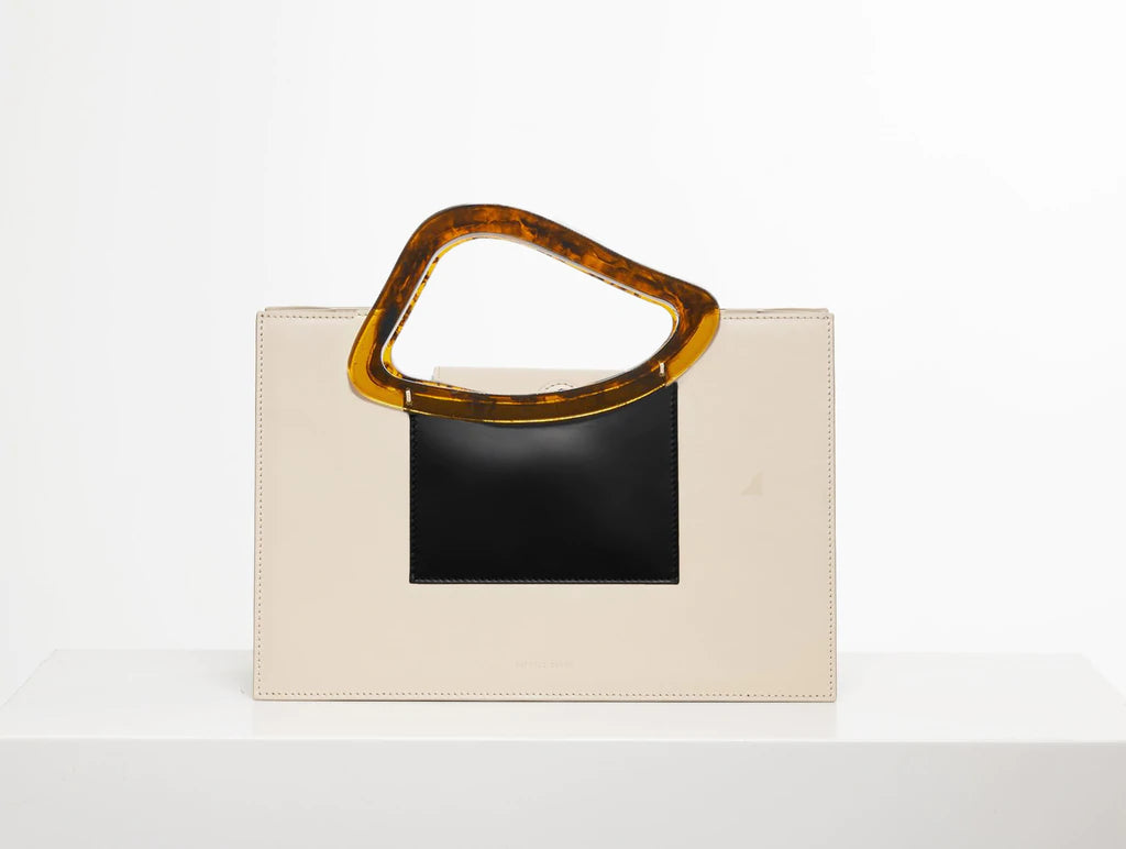 Beige black calf leather medium structured rectangle bag with bio resin handle and removable calf leather shoulder strap on a white stand