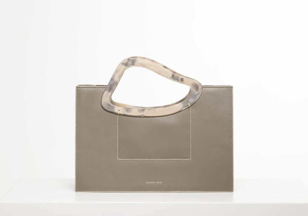 Taupe calf leather medium structured rectangle bag with bio resin handle and removable calf leather shoulder strap on a white stand