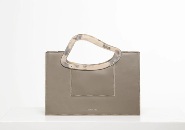 Taupe calf leather medium structured rectangle bag with bio resin handle and removable calf leather shoulder strap on a white stand