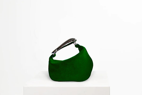 Green hand bag with metal handle on white stand