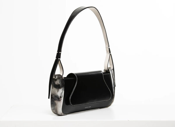 Black calf leather mini rectangle boguette bag with special resin cover companents on the sides. non-removable shoulder strap on a white stand