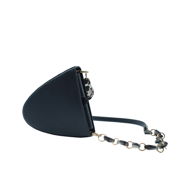 Flap topped oval structured anthracite calf leather cross body bag with an adjustable leather and natural resin chain linked strap on a white stand