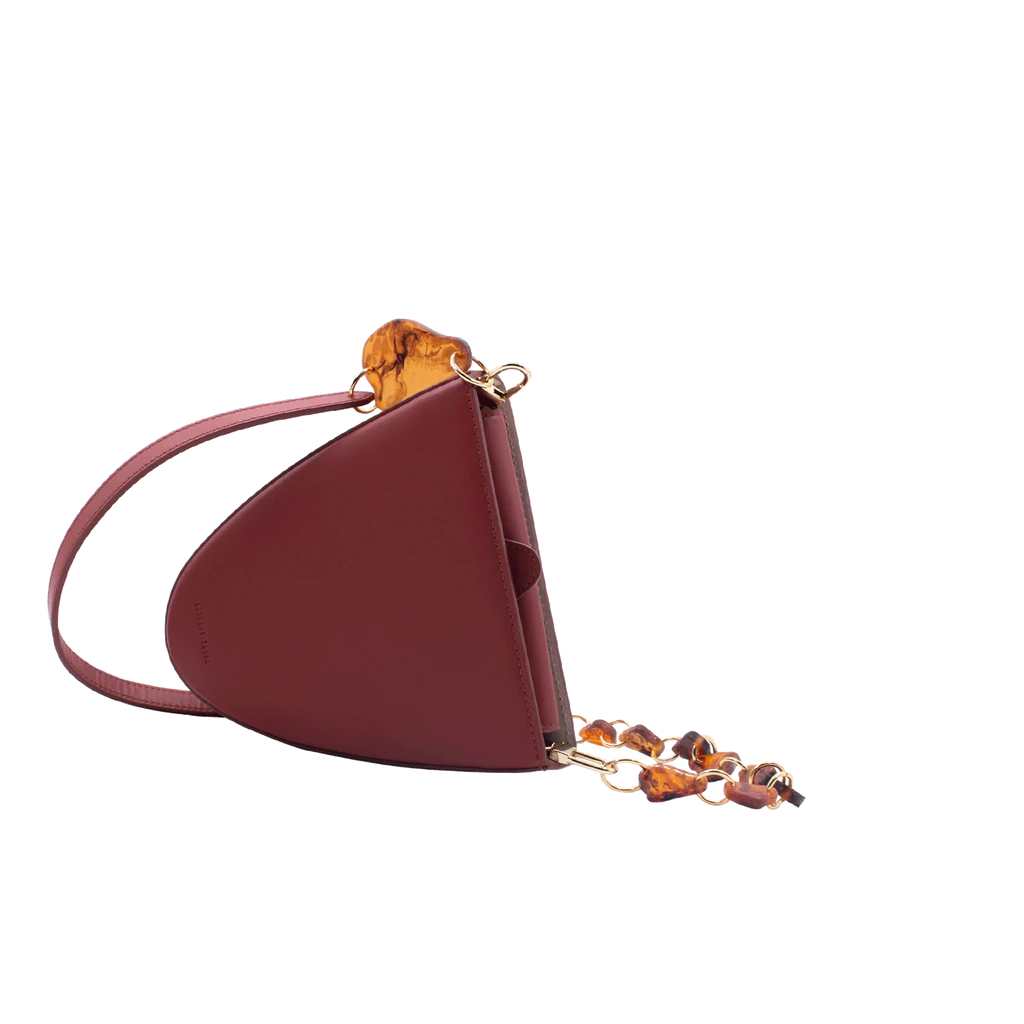 Flap topped oval structured brown calf leather cross body bag with an adjustable leather and natural resin chain linked strap on a white stand