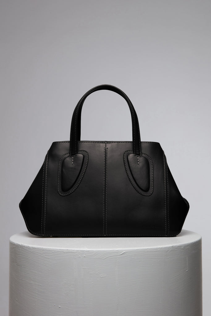 Black leather handbag over the white stand