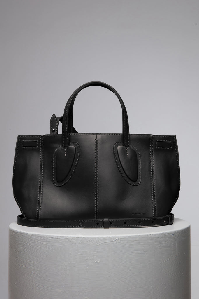 Black leather handbag over the white stand