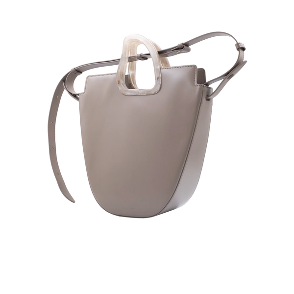 Flat topped oval structured taupe calf leather tote bag with natural resin round handles and a removable adjustable calf leather strap on a white stand