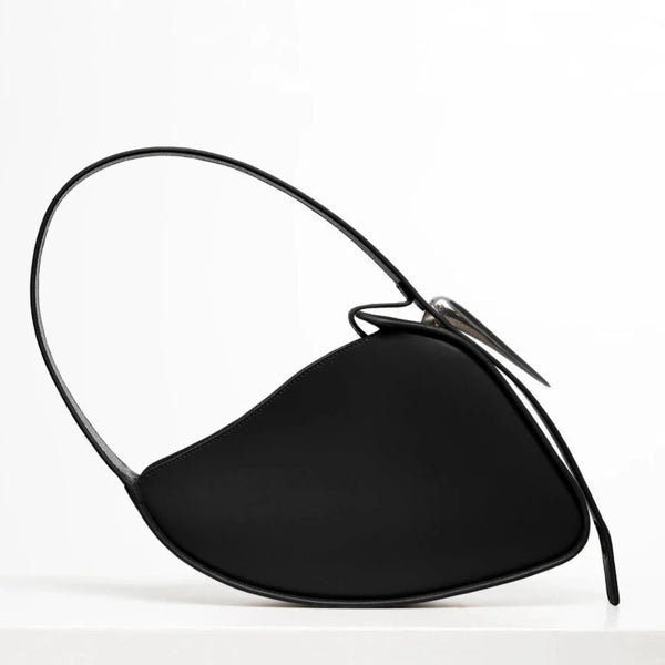 Flat topped oval structured saddle bag with bio resin accessories and non-removable but adjustable calf leather strap on a white stand