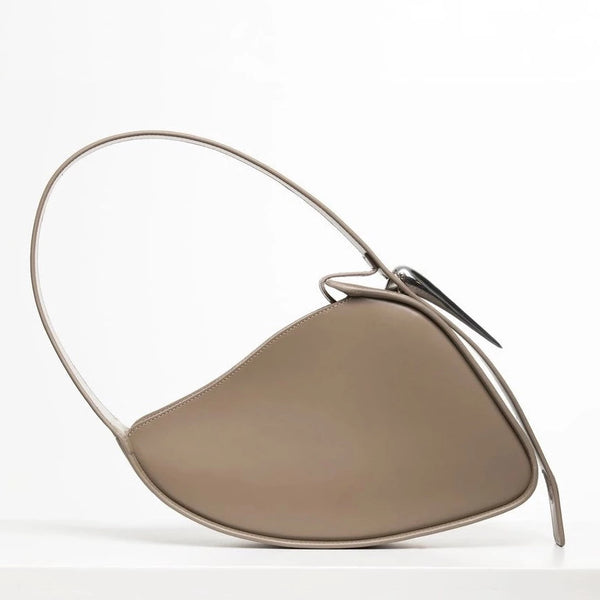Flat topped oval structured saddle bag with bio resin accessories and non-removable but adjustable calf leather strap on a white stand